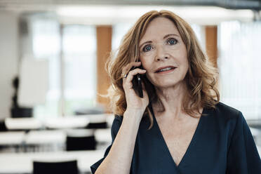 Businesswoman talking on smart phone in office - JOSEF03274
