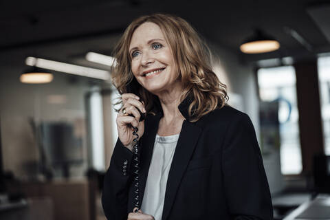 Schöne Geschäftsfrau im Gespräch am Telefon im Büro, lizenzfreies Stockfoto