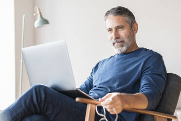 Businessman working on laptop while sitting at home - SBOF02577