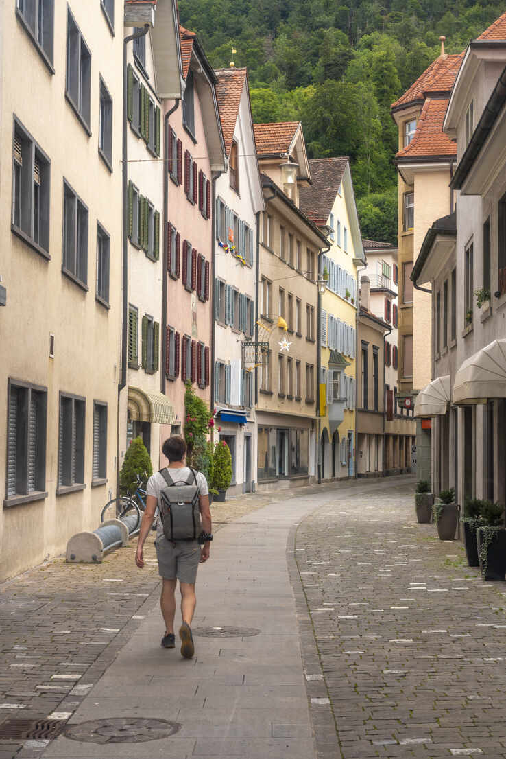 Explorer with backpack walking on Storchengasse street in old town of Chur