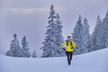 Weibliche Forscherin läuft im Schnee über den Berg im Heimgarten in Bayern, Deutschland - MRF02463