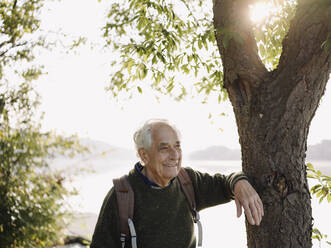 Älterer Mann lächelnd an einem Baum stehend - GUSF05053