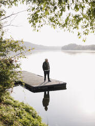 Man looking at view while standing on pier by lake - GUSF05056