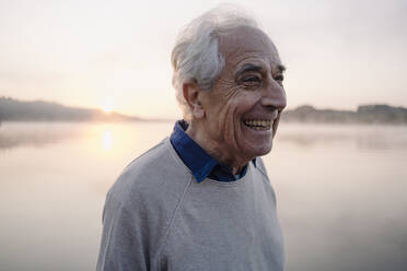 Happy man looking away while standing against lake - GUSF05125