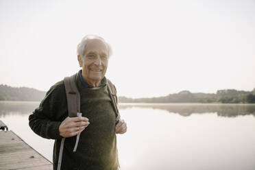 Senior explorer carrying backpack while standing on pier - GUSF05145