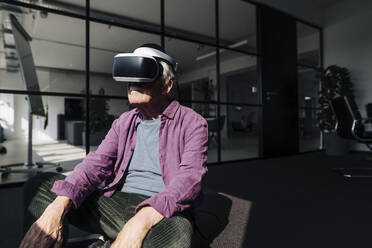 Unternehmer, der ein Virtual-Reality-Headset benutzt, während er im Büro sitzt - GUSF05160