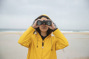 Frau mit Fernglas am Strand stehend - KBF00703