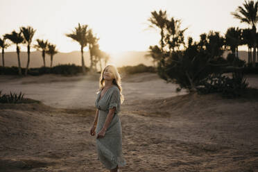 Junge Frau steht bei Sonnenuntergang am Strand - LHPF01361