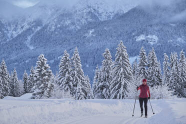 Ältere Frau beim Skifahren mit Skistock auf Schnee über Berg - MRF02467