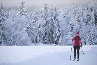 Frau in Warnkleidung beim Skifahren mit Skistock im Schnee - MRF02468