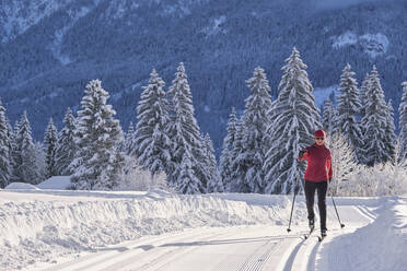 Weibliche Entdeckerin mit Skistock beim Skifahren über einen verschneiten Berg im Winter - MRF02470