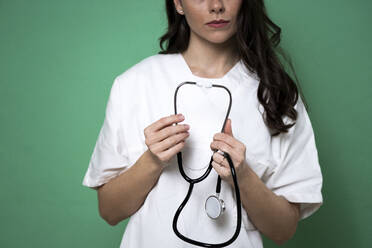Female doctor holding stethoscope in studio - GIOF10926