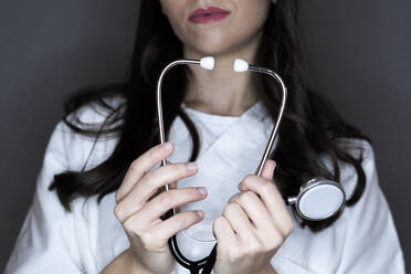 Young female doctor holding stethoscope in studio - GIOF10941