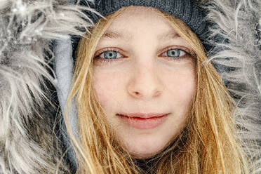 Close-up of girl wearing fur hat staring while smiling outdoors - OGF00822