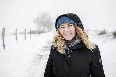 Blonde Frau im Schnee stehend im Urlaub - KMKF01516