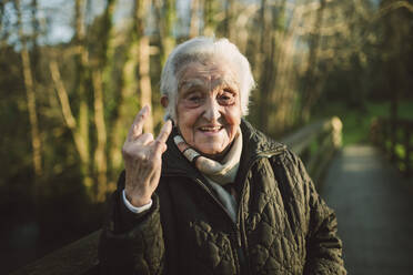 Fröhliche ältere Frau mit Hupzeichen an einem sonnigen Tag - RAEF02429