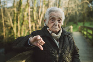 Unzufriedene ältere Frau mit Daumen-nach-unten-Geste im Winter - RAEF02431