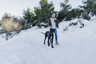 Junger Mann und Hund wandern im Winter im Schnee - EBBF02377