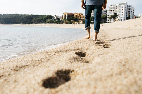 Älterer Mann, der an einem sonnigen Tag auf dem Sand am Strand spazieren geht - JRFF05018