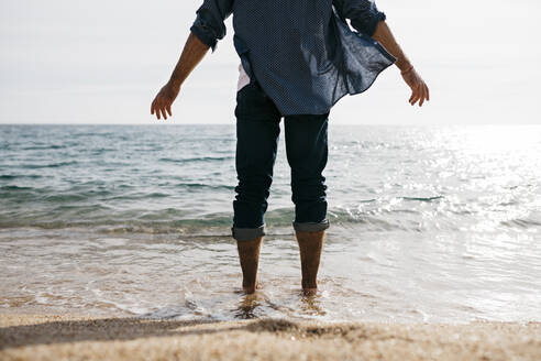 Älterer Mann steht am Rande des Wassers gegen den klaren Himmel am Strand - JRFF05029