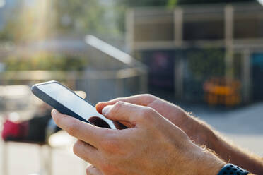 Close-up of businessman hand using mobile phone outdoors - BOYF01671