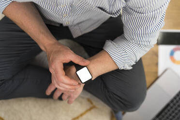 Businessman using smart watch while sitting at home - BOYF01733