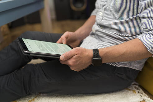 Businessman using digital tablet while sitting at home - BOYF01736