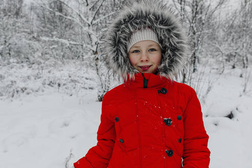Lächelndes Mädchen in warmer Kleidung in den Ferien im Wald stehend - OGF00831