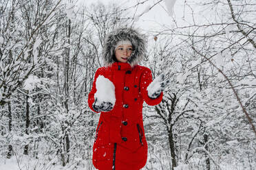 Mädchen, das den Schnee festhält und im Winter gegen den Wald blickt - OGF00834