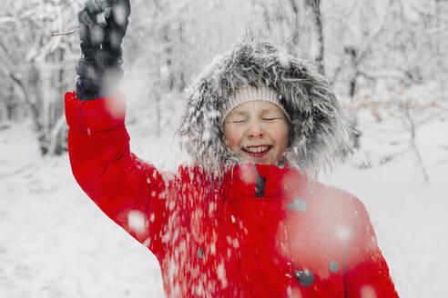 Mädchen, das eine Jacke trägt und Spaß hat, während es in den Ferien schneit - OGF00837