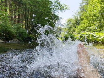 Frau, die im Ardennenwald in der Wallonie, Belgien, Wasser spritzt - GWF06851