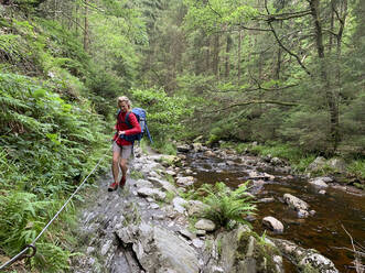Wanderin, die ein Seil hält, während sie durch das Tros-Maret-Tal im Ardennenwald in Wallonien, Belgien, wandert - GWF06854