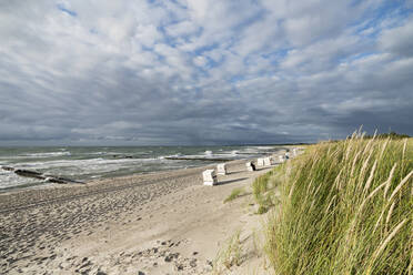 Bewölkter Himmel über vermummten Strandkörben am leeren Strand - MYF02334