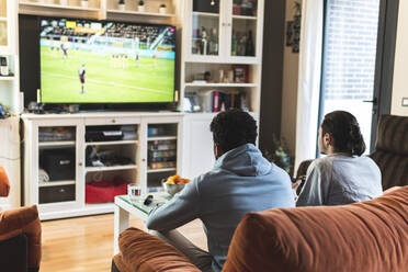 Junge männliche Freunde spielen Fußball vor dem Fernseher im heimischen Wohnzimmer - JAQF00200