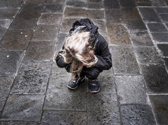 Sad lost girl crying while crouching on footpath during rainy season - HAMF00794