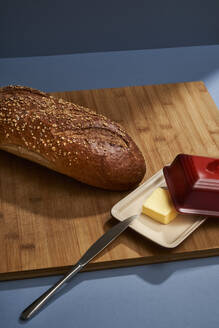 Laib Brot und Butter auf dem Schneidebrett im Haus - BOYF01760