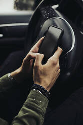 Young man text messaging through smart phone in car - ACPF01083