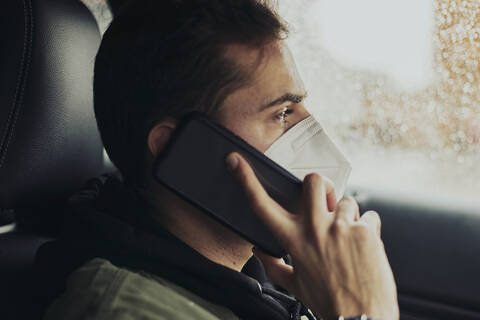 Young man talking through mobile phone while sitting in car during COVID-19 stock photo