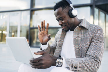 Mann trägt Kopfhörer und gestikuliert bei einem Videotelefonat mit einem Laptop - MPPF01430