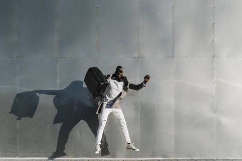 Mann mit Koffer springt durch Metallwand - MPPF01433