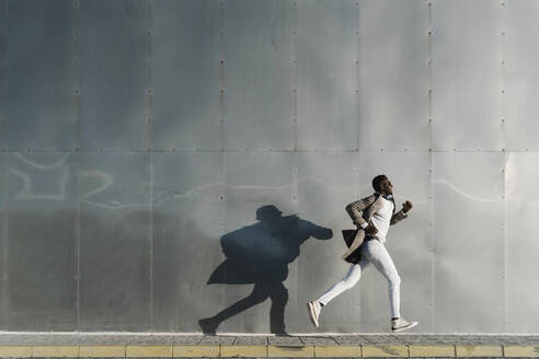 Afrikanischer Mann läuft an einer Metallwand vorbei - MPPF01437