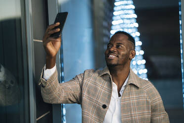 Lächelnder Mann, der nachts ein Selfie über sein Smartphone macht - MPPF01461