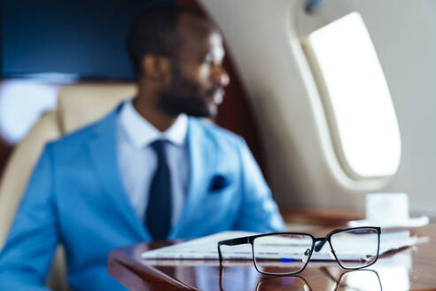 geschäftsmann mit Brille und Zeitung auf dem Tisch im Privatjet - OIPF00242