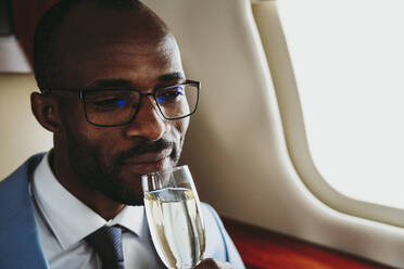 Geschäftsmann trinkt Champagner im Privatjet - OIPF00256