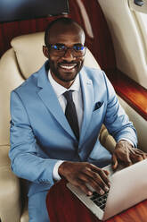 Junger männlicher Unternehmer mit Laptop im Flugzeug - OIPF00274