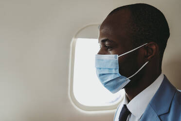 Male entrepreneur with protective face mask in airplane - OIPF00292