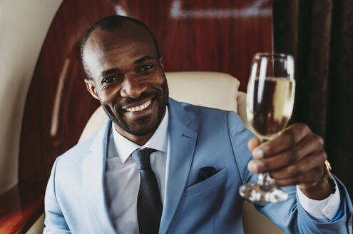 Eleganter Geschäftsmann mit Champagner auf Reisen im Flugzeug - OIPF00304