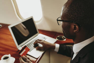 Geschäftsmann macht Online-Zahlung durch Laptop im Flugzeug - OIPF00329