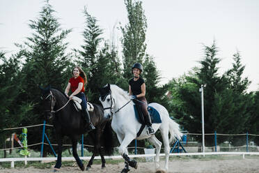 Glückliche Freundinnen reiten auf Pferden in einem Bauernhof - MRRF00853