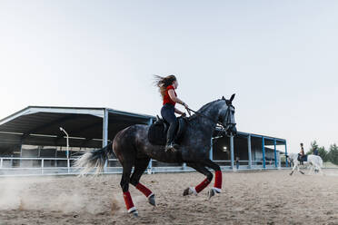 Junge Frau beim Reiten auf einem Bauernhof am Wochenende - MRRF00860